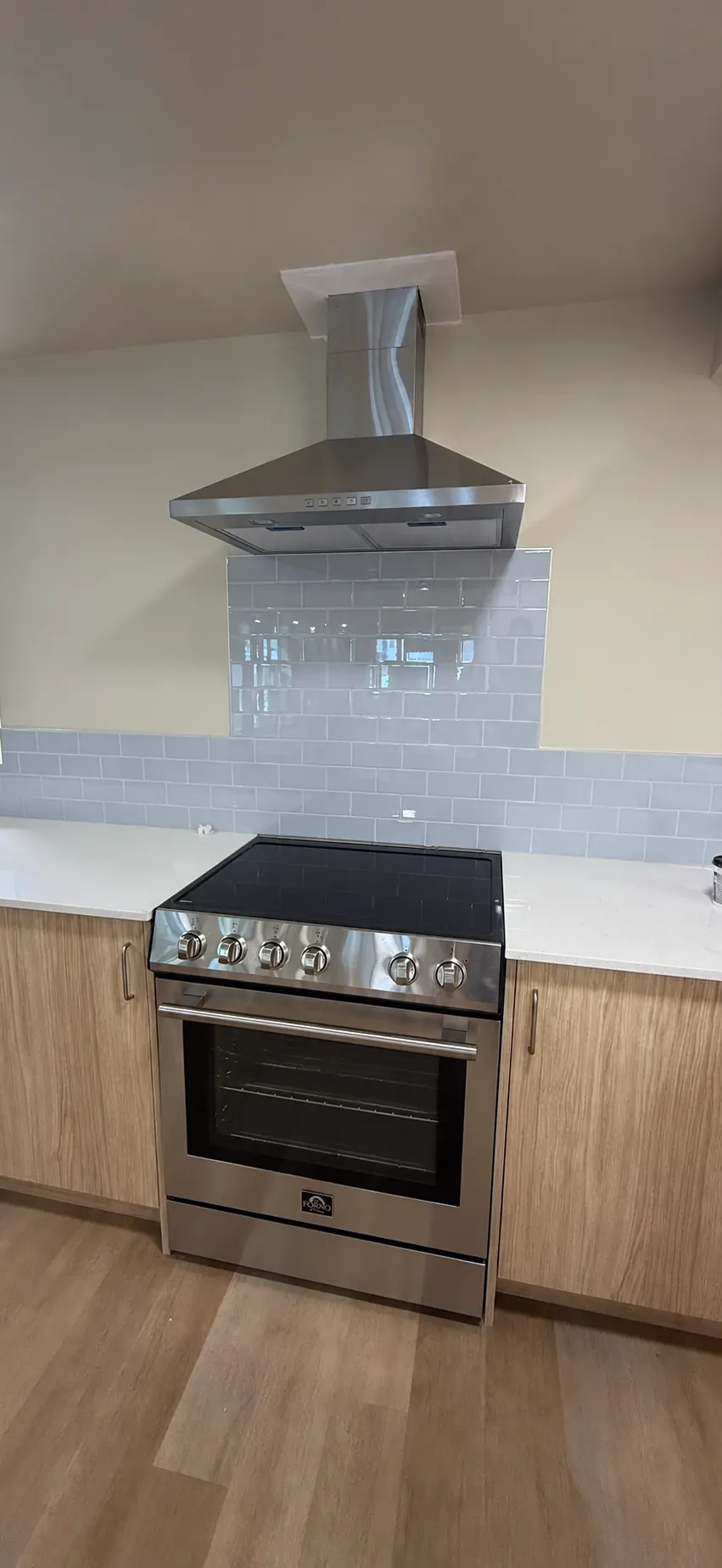 New suite kitchen with range, hood fan and tile backsplash